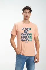 Remera color durazno con estampado azul en el frente con texto.