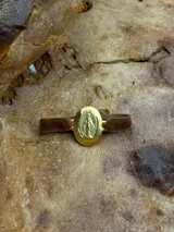 Pulsera elástica de terciopelo marrón con medalla ovalada dorada de la Virgen María.