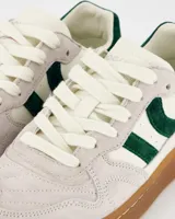 Championes deportivos Coolway modelo Goal, color blanco hueso con detalles en verde oscuro y suela marrón. Confeccionados en serraje y piel, con cordones planos de algodón intercambiables.