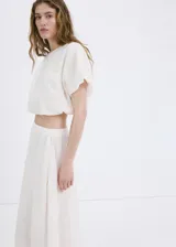 Falda midi evasé de color blanco, confeccionada en algodón con detalles bordados tonales, cintura elástica y forro interior.