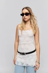 Vestido corto blanco confeccionado en encaje con silueta ajustada al cuerpo, escote recto y breteles finos.
