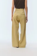 Pantalón de lino color tostado, de tiro alto y corte amplio con perneras rectas. Cuenta con pasacintos, bolsillos laterales y bolsillos traseros con solapa.