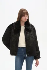 Campera de piel sintética color negro, con cuello, manga larga y cierre frontal. Presenta un diseño de corte holgado y textura suave.