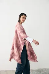Ruana de tejido de punto con diseño teñido artesanalmente en tonos rosados y beige, con terminación de flecos en el ruedo.