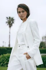 Blazer de lino blanco con solapas y detalles de volados en los puños, de corte recto y clásico.