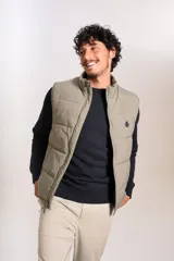 Chaleco puffer de corte regular, color beige, con cierre frontal y cuello alto. Presenta un diseño acolchado horizontal y logo bordado en el pecho.