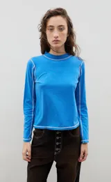 Remera de manga larga color azul, con cuello tipo tortuga y costuras expuestas en color blanco que resaltan el diseño. Presenta un corte recto y ajuste cómodo.