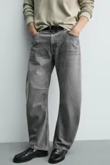 Jeans de denim de algodón en color negro con efecto lavado, corte amplio y silueta curva tipo barrel fit con pinzas en las rodillas. Presenta diseño clásico de cinco bolsillos y cierre frontal con cremallera y botón metálico.