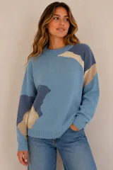 Buzo tejido de punto con diseño abstracto en tonos celeste, azul marino y beige, cuello redondo, mangas largas y puños y ruedo elásticos acanalados.