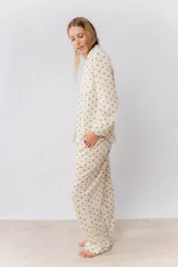 Pijama de algodón estampado con motas verdes y marrones, compuesto por una camisa de manga larga abotonada y un pantalón con elástico en la cintura y dos bolsillos.