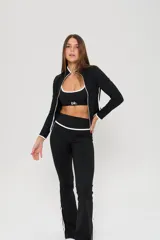Conjunto deportivo de tres piezas compuesto por un top con breteles finos, una campera entallada con cierre frontal y una calza semioxford. Todas las prendas son de color negro con detalles de ribetes blancos en los bordes.