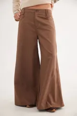 Pantalón de tiro medio con corte wide leg, confeccionado en tencel. Presenta un diseño con cortes curvos en las piernas, bolsillos delanteros y cierre frontal con botón.