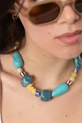 Collar corto con piedras y cuentas en tonos turquesa, azul, amarillo y beige de formas irregulares.
