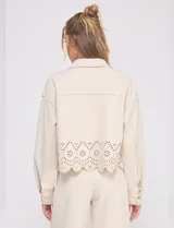 Chaqueta color beige de suede marca Allie Rose, con cuello con solapa, abertura central con botones, bolsillos delanteros y ruedo con diseño calado.