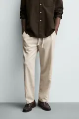 Pantalón de corte relajado confeccionado en una mezcla de algodón y lino. Presenta cintura elástica con cordón ajustable, bolsillos laterales y bolsillos traseros de vivo.