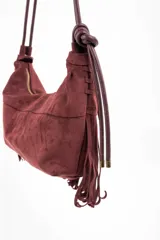 Cartera de hombro con diseño de flecos largos en la parte frontal, confeccionada en material sintético con textura de gamuza. Cuenta con una correa larga ajustable y cierre superior.