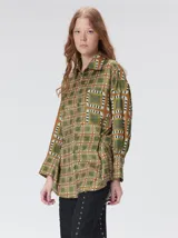 Camisa de seda con estampado geométrico de cuadrados en tonos rojizos y marrones. Presenta cuello camisero, cierre frontal con botones, bolsillo en el pecho y mangas largas con puños abotonados.