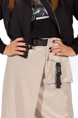 Falda midi color beige de simil cuero, con corte irregular, bolsillo lateral y cinturón con hebilla plástica.