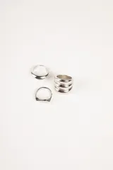 Set de anillos plateados con diferentes diseños: uno liso y grueso, otro con forma de sello y un tercero con varios anillos finos unidos.