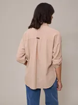 Camisa color beige de algodón y lino, con cuello clásico, cierre frontal con botones, mangas largas con puños abotonados, dos bolsillos con solapa en el pecho y corte holgado.