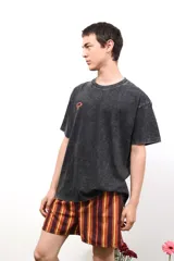 Remera de algodón con efecto lavado ácido en color negro, de corte holgado y manga corta. Presenta un estampado artístico en color rojo en la parte posterior con la palabra Caper.