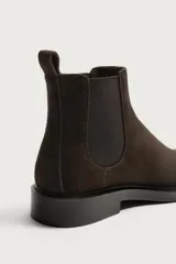Bota chelsea de cuero con acabado de serraje color negro, con elásticos laterales y tira trasera para facilitar el calce.