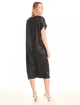 Vestido midi negro de satén con escote en V profundo y ribete de strass. Presenta una silueta relajada y fluida con corte oversized, mangas cortas amplias y una pequeña tabla central debajo del escote que genera un drapeado natural.
