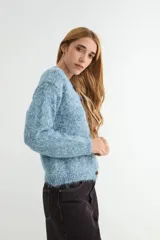 Cardigan de tejido de punto jaspeado en tonos rosados y violetas, con cuello redondo y cierre frontal de botones marrones.