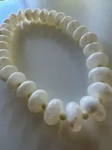 Collar de cuentas redondas y aplanadas con efecto marmolado en tonos grisáceos, con cierre metálico dorado.