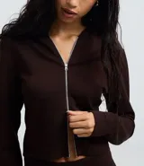 Campera corta con capucha fija, cierre frontal con cremallera y mangas largas, confeccionada en tejido modal con acabado satinado.