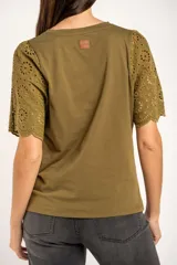 Remera de algodón peinado color negro, con mangas cortas de broderie con diseño calado y terminación festoneada. Presenta un corte oversize y cuello redondo.