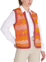 Chaleco sin mangas estilo boho, con estampado de ondas en tonos naranja, rosado y amarillo. Presenta bordes con detalles geométricos en color bordó y cierre frontal abierto.