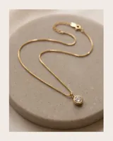 Collar de bronce con cadena fina y dije redondo con circonia blanca engastada.