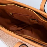 Cartera tipo tote de rafia sintética con rayas horizontales en tonos beige y blanco, terminaciones en eco cuero negro y herrajes metálicos dorados. Tiene doble asa fija y bolsillo interno con cierre.