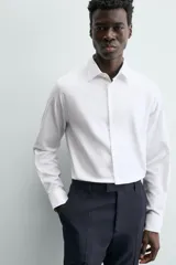 Camisa blanca de manga larga con cuello italiano y puños abotonados, confeccionada en tejido de algodón.