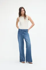 Jean wide leg color azul medio, con amplitud de piernas y tajo en el bajo.
