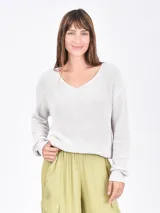 Buzo tejido de punto color beige, con escote en V y mangas largas holgadas.