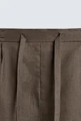 Bermuda de lino color blanco hueso, de corte relajado y tiro medio. Presenta cintura elástica ajustable con cordón, pliegues frontales y bolsillos laterales y trasero.
