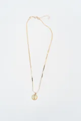 Collar de cadena tipo serpiente en tono dorado con dije circular central que contiene una piedra semipreciosa clara.