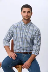 Camisa sport de manga larga con estampado de cuadros en tonos azules, grises y blancos. Presenta cuello con botones, cierre frontal abotonado y un bolsillo pequeño en el pecho.