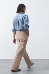 Pantalón de pana color marrón chocolate, de corte recto con bolsillos laterales y cierre frontal.