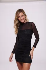 Vestido corto negro de poliéster y elastano, con cuello alto de tul y mangas largas de tul con pequeños apliques brillantes.