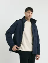 Campera 2 en 1 azul marino con capucha desmontable, cierre frontal con solapa de botones a presión y bolsillos laterales con cierre.