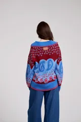 Sweater de tejido de punto con diseño estampado tipo paisley y floral en tonos azul, rojo y bordó. Presenta un cuello polo con escote en V, mangas largas y un corte holgado.