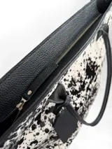 Cartera tipo tote de cuero genuino color marrón oscuro con textura de reptil. Cuenta con doble asa de hombro, cierre superior y un dije colgante de cuero a tono.