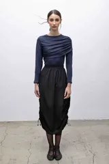 Top negro de mangas largas con frunces en el hombro izquierdo.