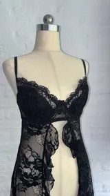 Top de encaje negro con diseño de corpiño tipo bralette y falda larga abierta al frente, con terminaciones de puntilla.