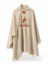 Ruana color beige con flecos en los bordes y bordado frontal en marrón que incluye el logotipo de la marca Bagual junto al mapa de Uruguay con un gaucho a caballo. Cuenta además con una etiqueta de cuero sintético en el cuello.
