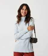 Suéter de tejido de punto en color celeste claro, con cuello alto, mangas raglán y puños y ruedo acanalados. Presenta un diseño con el ruedo trasero ligeramente más largo.