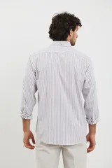 Camisa sport de hombre con cuello button-down, manga larga y diseño a rayas verticales blancas y marrones. Presenta un bolsillo de parche en el pecho y botones de madera.